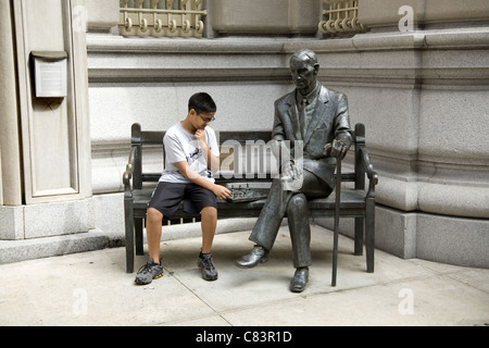 Controllare mate. Il ragazzo si presenta come un giocatore di scacchi con la statua di Jan Karski, un famoso membro della Polonia di II Guerra Mondiale in metropolitana in NYC. Foto Stock