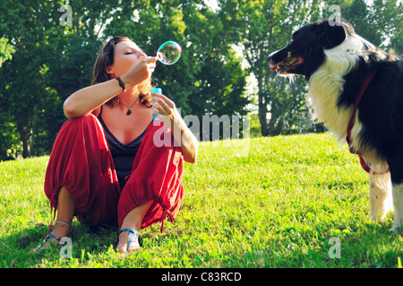 La donna a soffiare bolle per il cane in posizione di parcheggio Foto Stock