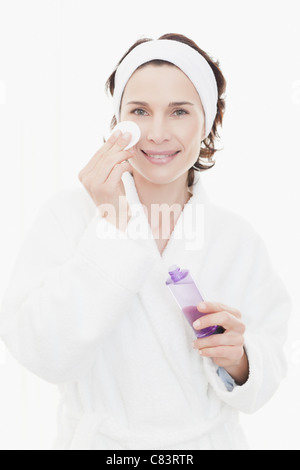 Donna in accappatoio detersione viso Foto Stock