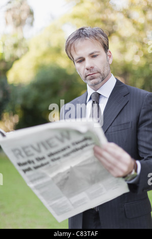 Imprenditore quotidiano di lettura in posizione di parcheggio Foto Stock