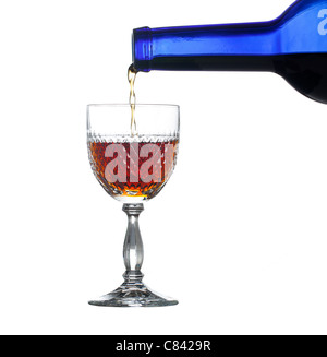 Sherry, la porta o il whisky versata da blu bottiglia di vino in un elegante taglio di vetro e isolata contro bianco Foto Stock