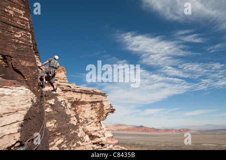 Un rocciatore è ascendente alcuni grandi in arenaria roccia rossa, vicino a Las Vegas in Nevada. Foto Stock