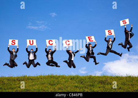 Happy businessman holding successo testo e saltare sul campo verde Foto Stock