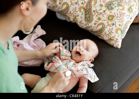 Madre caucasica cambiando la nostra bambina gli abiti Foto Stock