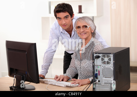 Giovane uomo e donna più anziana utilizzando un computer Foto Stock
