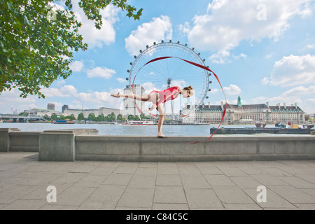 Ginnasta fa roteare nastro su una strada di città Foto Stock