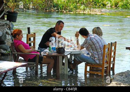 AKYAKA, Turchia. Una famiglia turca di mangiare la prima colazione e il raffreddamento i loro piedi nelle limpide acque del fiume Azmak. 2011. Foto Stock