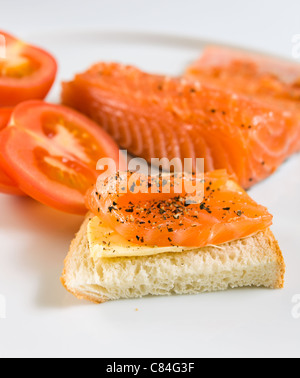 Sandwich con salmone e pomodoro su una piastra bianca. Foto Stock