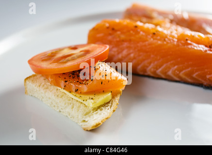 Sandwich con salmone e pomodoro su una piastra bianca. Foto Stock