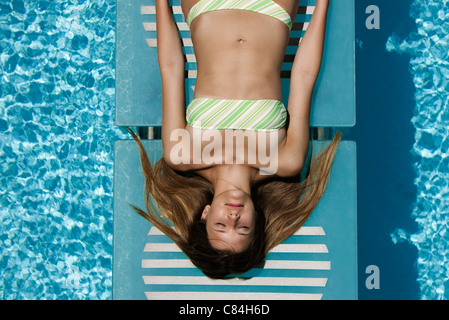 Giovane donna a prendere il sole in piscina Foto Stock
