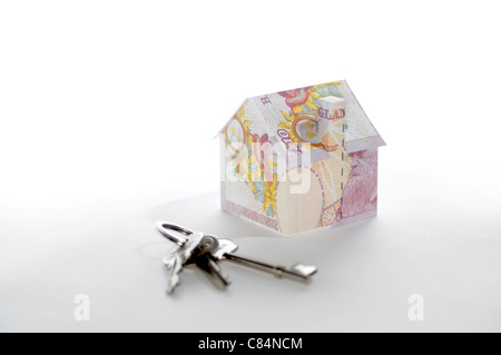 Modello di casa piegato con British pound banconote e le chiavi Foto Stock