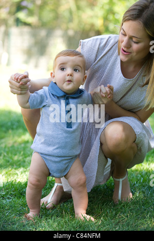 Madre aiutare baby stand all'aperto Foto Stock