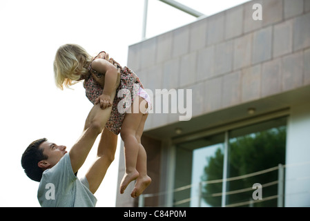 Padre il sollevamento giovane figlia in aria Foto Stock