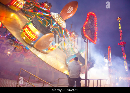 Fiera lavoratore la visione di una giostra luna park guidare di notte a Goose Fair, Nottingham, Inghilterra, Regno Unito Foto Stock