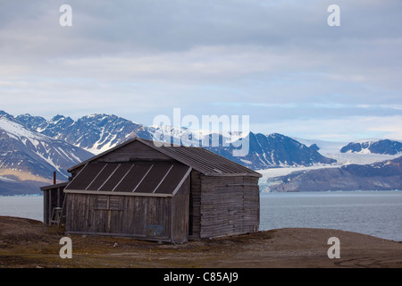 Capanna di legno Kongsfjord, con il ghiacciaio in fondo alla ricerca scientifica internazionale base di Ny Alesund, Svalbard. Foto Stock