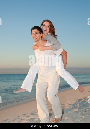 Piggybacking uomo donna sulla spiaggia, Reef Playacar Resort e Spa, Playa del Carmen, Messico Foto Stock