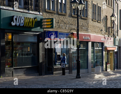 Donna di ottenere denaro da 'buco nel muro", Keighley, West Yorkshire, Inghilterra, Regno Unito Foto Stock