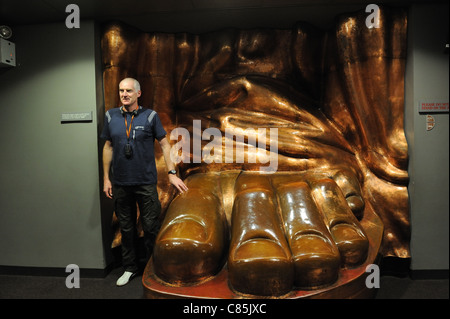 Un visitatore al museo nel piedistallo della Statua della Libertà sorge accanto a una replica di rame della statua il piede. Foto Stock