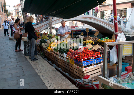 Un fruttivendolo su una barca a Venezia Foto Stock