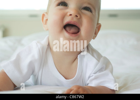 Il Bambino giacente sul letto, cercando con la bocca aperta Foto Stock