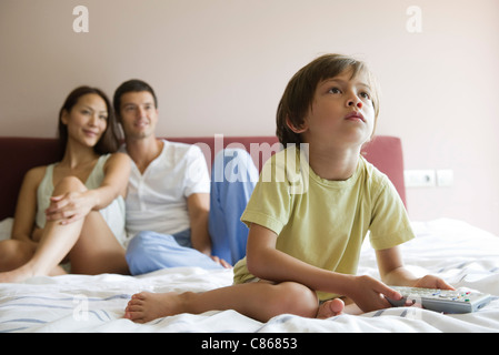 Ragazzo guardando la TV nel letto con i genitori Foto Stock