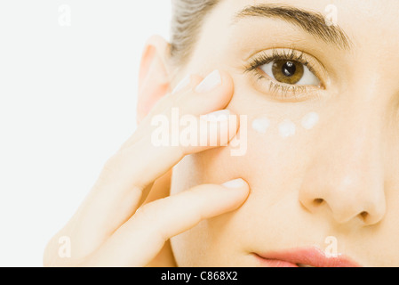 Donna applicando undereye crema, close-up, ritagliato Foto Stock