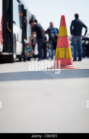 Cono di sicurezza al aérodrome di un aeroporto (con passeggeri che salgono su un bus navetta in background) Foto Stock