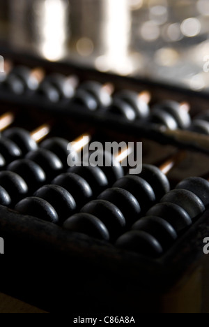 In prossimità di un vecchio abacus cinese contro lo sfondo delle monete Foto Stock