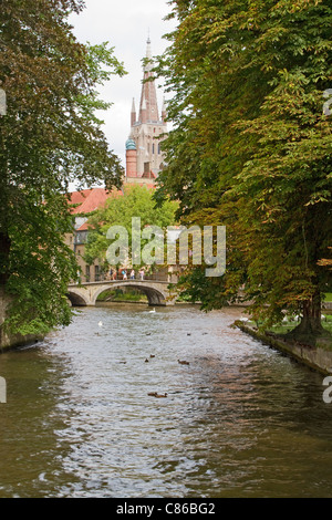 La Chiesa di Nostra Signora a Bruges, Belgio, come si vede tra gli alberi che la linea fino ad un canale Foto Stock