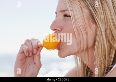 Donna di mangiare ghiaccioli sulla spiaggia Foto Stock