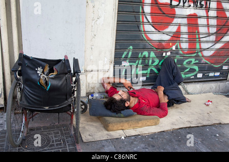 Senzatetto uomo dorme sulle strade di Omonia. In Atene scene come questa sono comuni, la gente disperata nel terribile salute. Foto Stock