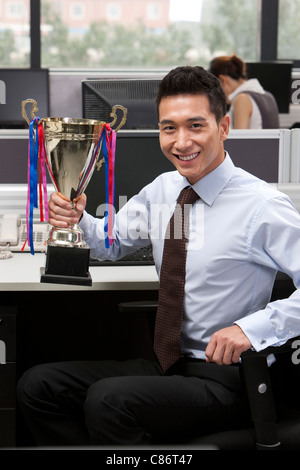 Businssman tenendo un trofeo Foto Stock