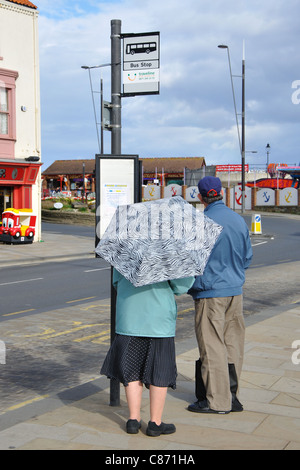 Coppia senior in attesa di un autobus, Scarborough, North Yorkshire, Inghilterra, Regno Unito Foto Stock