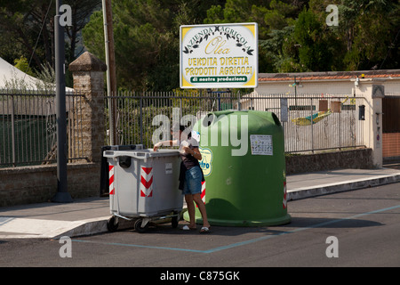 Donna mettendo in plastica del contenitore di riciclaggio a Bracciano Italia Foto Stock