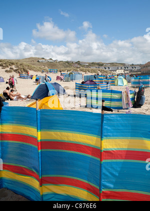 Un sacco di coloratissimi frangiventi sulla spiaggia a Perranporth su una giornata d'estate, Cornwall, Regno Unito Foto Stock