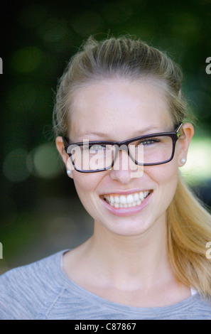 In Germania, in Baviera, Schaeftlarn, ravvicinata di una giovane donna con occhiali spessi, ritratto, sorridente Foto Stock