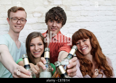 Germania, Berlino, giovani uomini e donne tenendo le bottiglie di birra, sorridente, ritratto Foto Stock