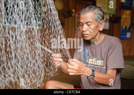 Iban longhouse chief mende sue reti da pesca al Nanga Sumpa longhouse nel Sarawak, Borneo Malaysia Foto Stock