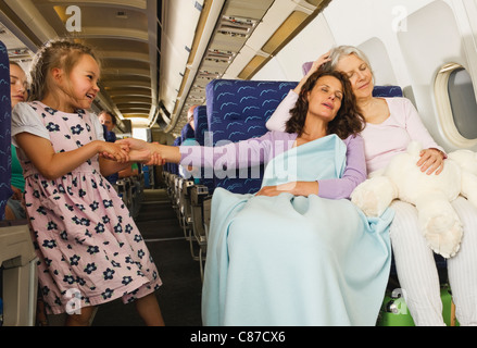 Germania - Monaco di Baviera, donne dormire e ragazza tirando la donna la mano in classe economy aereo di linea Foto Stock