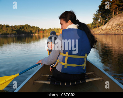 La donna in una canoa con un bambino. Tramonto rientrano la natura paesaggio. Sguazzare in Killarney Provincial Park, Ontario, Canada. Foto Stock