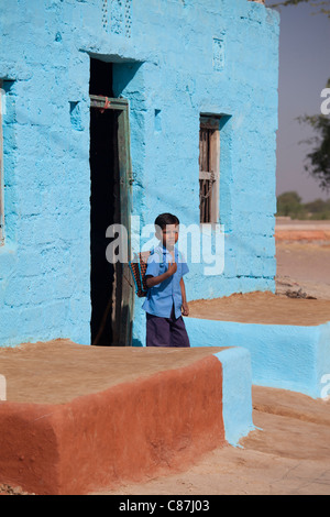 Boy esce di casa in bramino indù di casta alta villaggio di Dhudaly voce per la scuola nel Rajasthan, India settentrionale Foto Stock