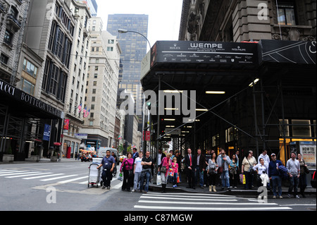 Linea di persone in attesa di attraversare West 55th Street, angolo del Peninsula Hotel, guardando verso sud, la Fifth Avenue, New York Foto Stock