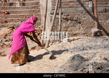 Donna indiana in sari mescolare cemento mentre si lavora sul sito in costruzione al villaggio Khore nel Rajasthan, India settentrionale Foto Stock