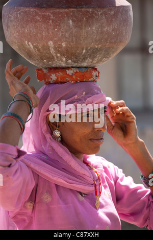 Donna indiana in sari il recupero dei vasi d'acqua dal pozzetto a Jawali villaggio in Rajasthan, India settentrionale Foto Stock