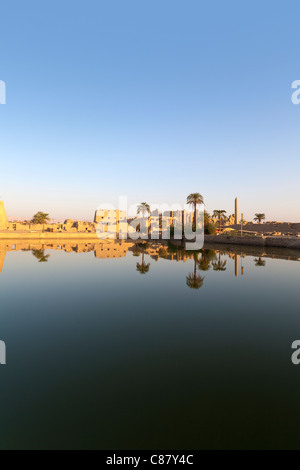 Vista al tramonto sul lago sacro verso i tralicci e Hypostyle Hall presso il Tempio di Karnak, riva orientale del Nilo Luxor Egitto. Foto Stock