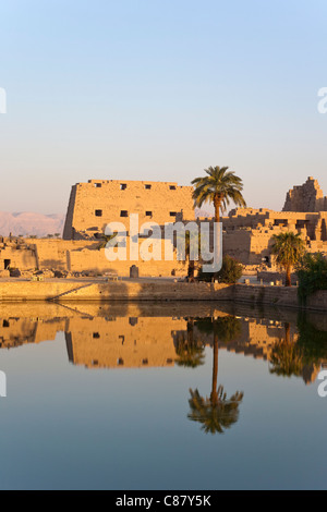 Vista al tramonto sul lago sacro verso i tralicci e Hypostyle Hall presso il Tempio di Karnak, riva orientale del Nilo Luxor Egitto. Foto Stock