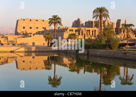 Vista al tramonto sul lago sacro verso i tralicci e Hypostyle Hall presso il Tempio di Karnak, riva orientale del Nilo Luxor Egitto. Foto Stock
