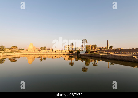 Vista al tramonto sul lago sacro verso i tralicci e Hypostyle Hall presso il Tempio di Karnak, riva orientale del Nilo Luxor Egitto. Foto Stock