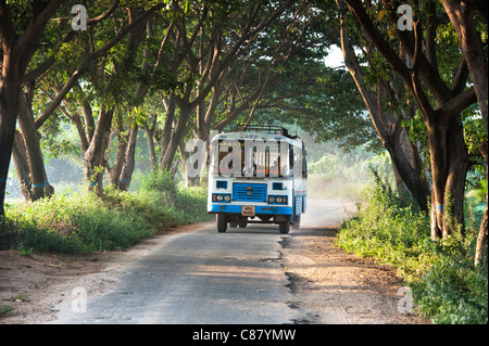 Indian bus / pullman viaggiano lungo una strada alberata in campagna. Andhra Pradesh, India Foto Stock