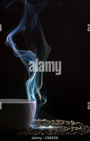 Bollitore per tè e fumo blu su sfondo nero Foto Stock